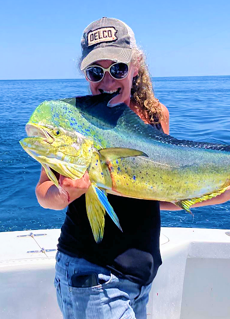 Young lady angler showing off her big mahi by biting its fin. Lady angler showing her big mahi.