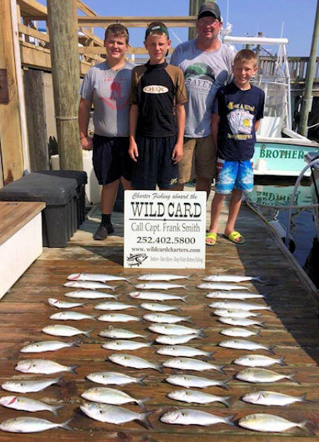 Happy young anglers showing off near shore catch of bluefish Young anglers showing off catch of bluefish